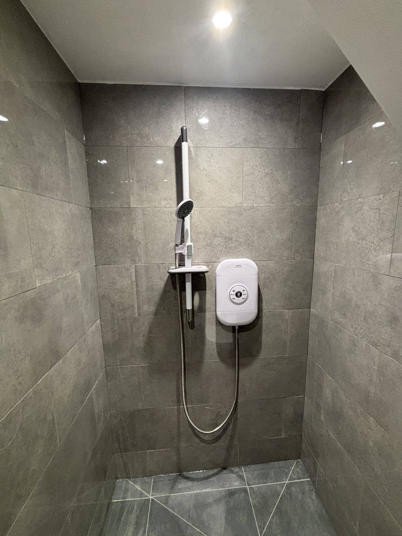Grey tiled shower cubicle with electric shower unit