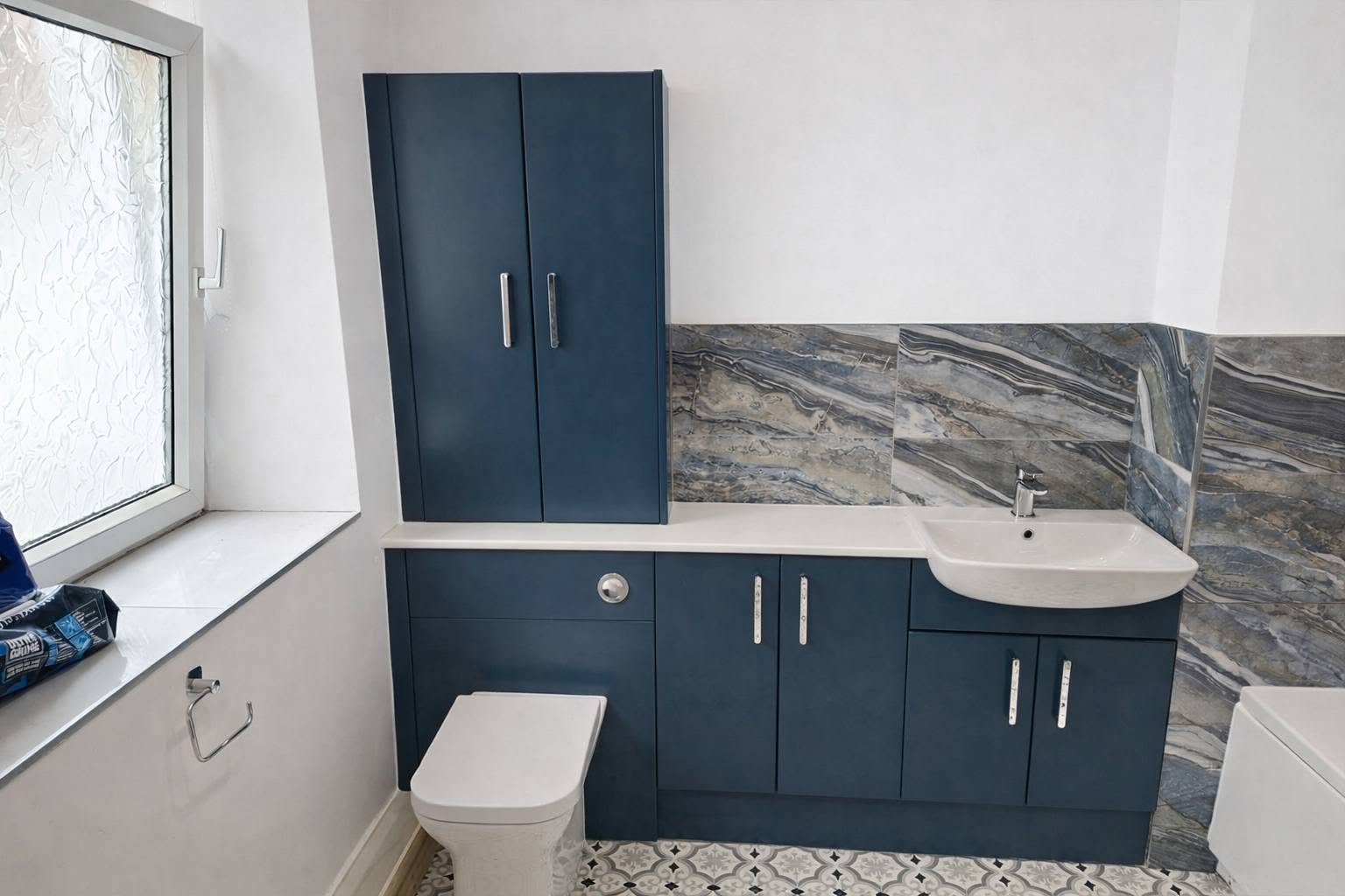 Navy blue fitted bathroom furniture with marble splashback