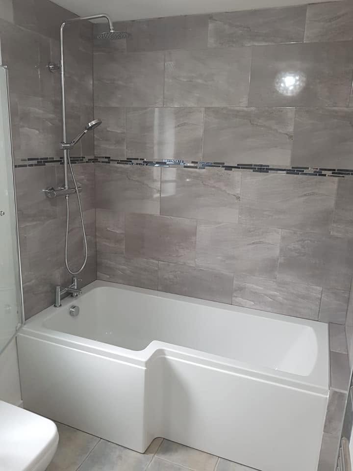 L-shaped bath with rainfall shower and grey wall tiles