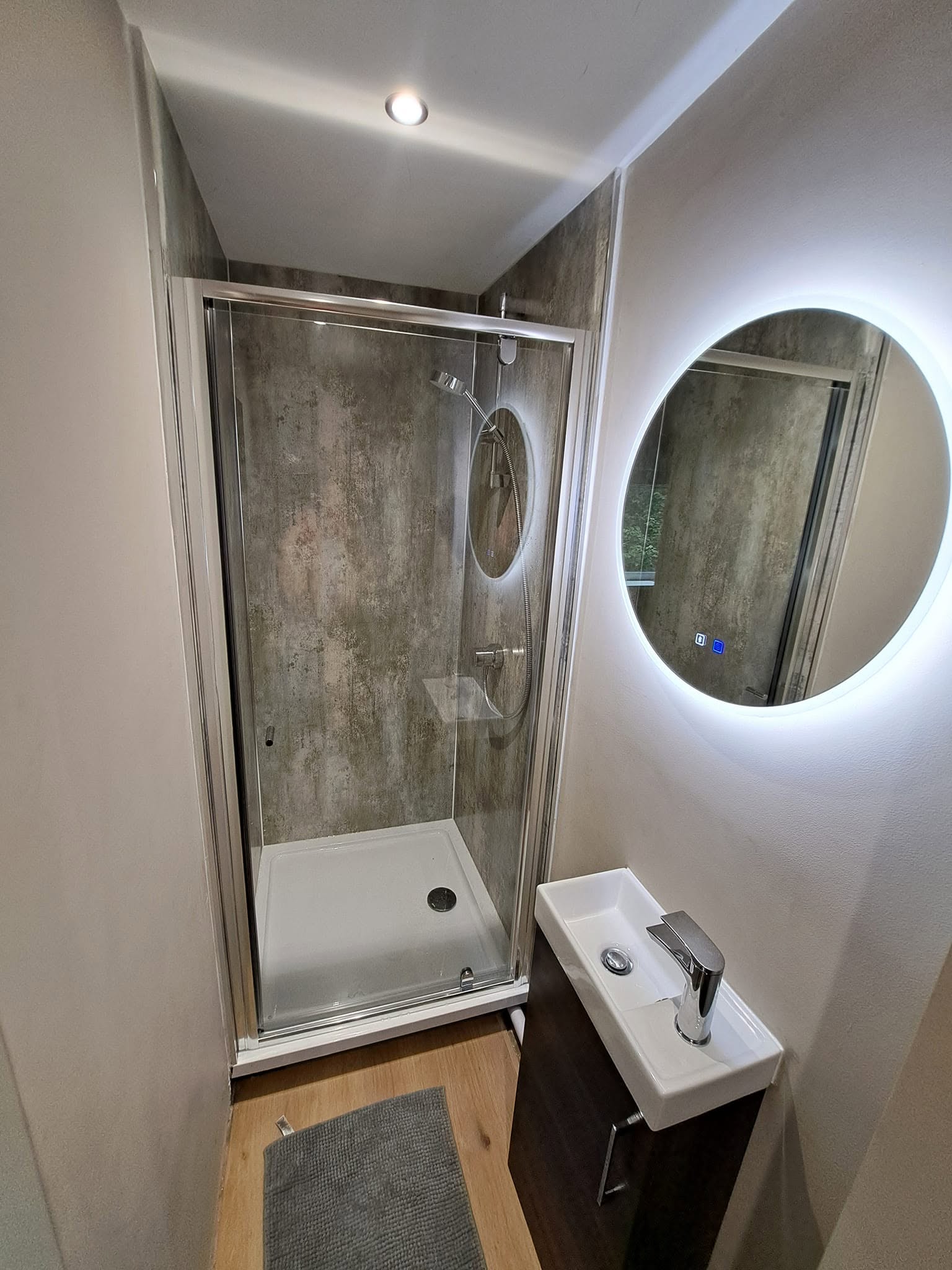 Compact ensuite with backlit mirror and shower cubicle