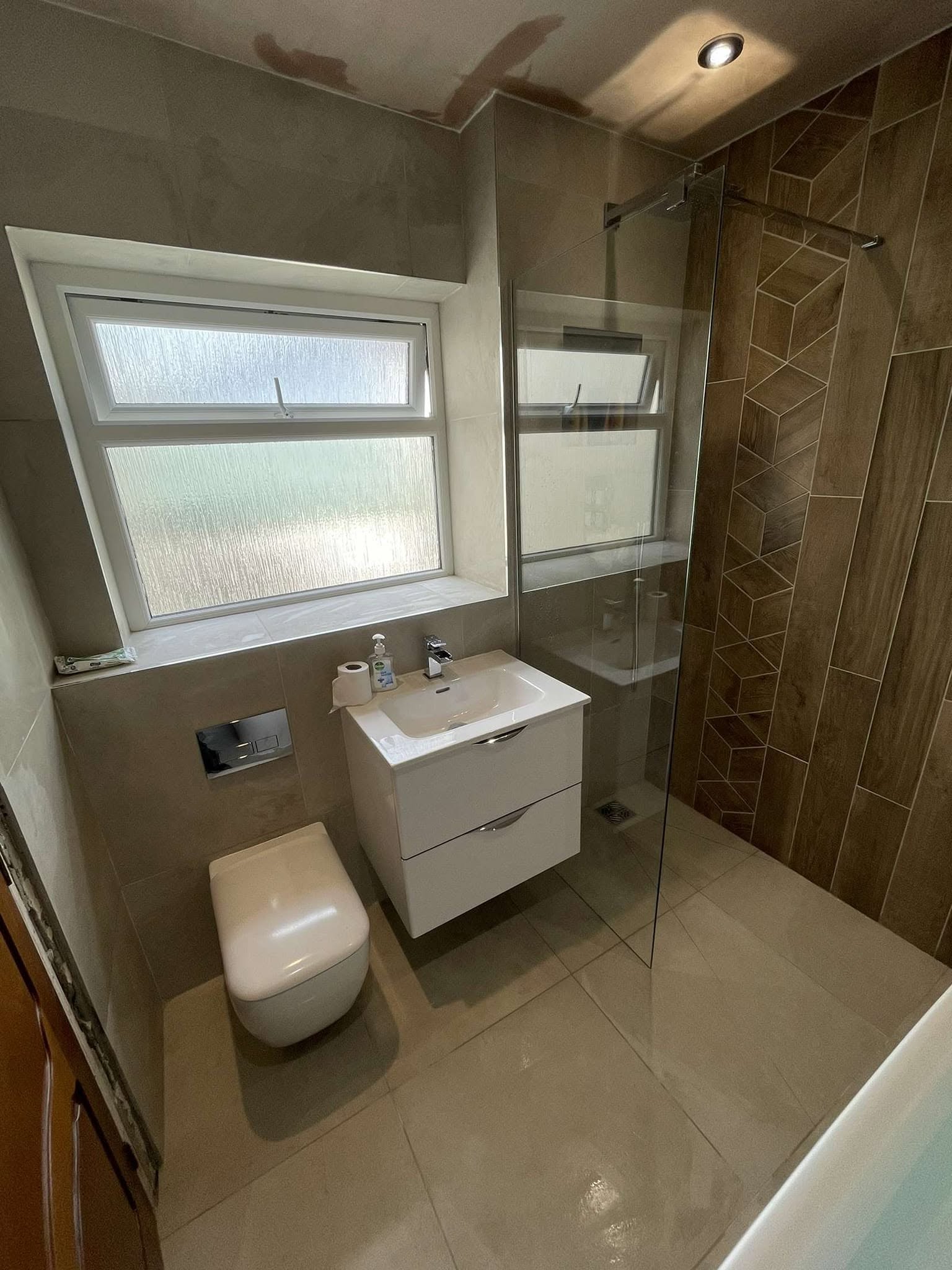 Contemporary bathroom with wall-hung basin, toilet and glass shower